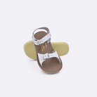 Two toddler sized 1700 Surfer style sandals with white straps and beige insoles.  One standing with the sole facing the camera. The second is laying diagonally over the top left edge of the sole.