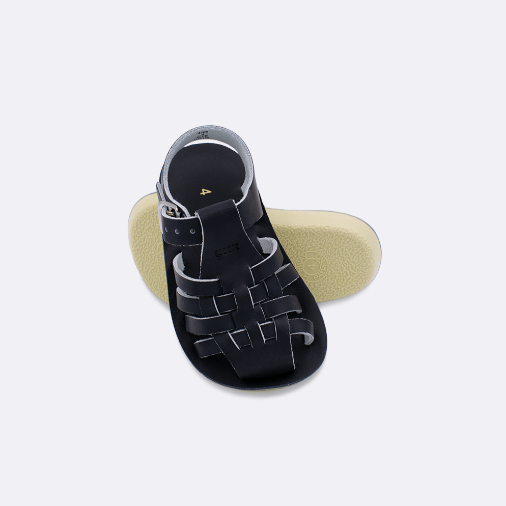 Two baby sized 4200 Sailor style sandals with black straps and black insoles.  One standing with the sole facing the camera. The second is laying diagonally over the top left edge of the sole.