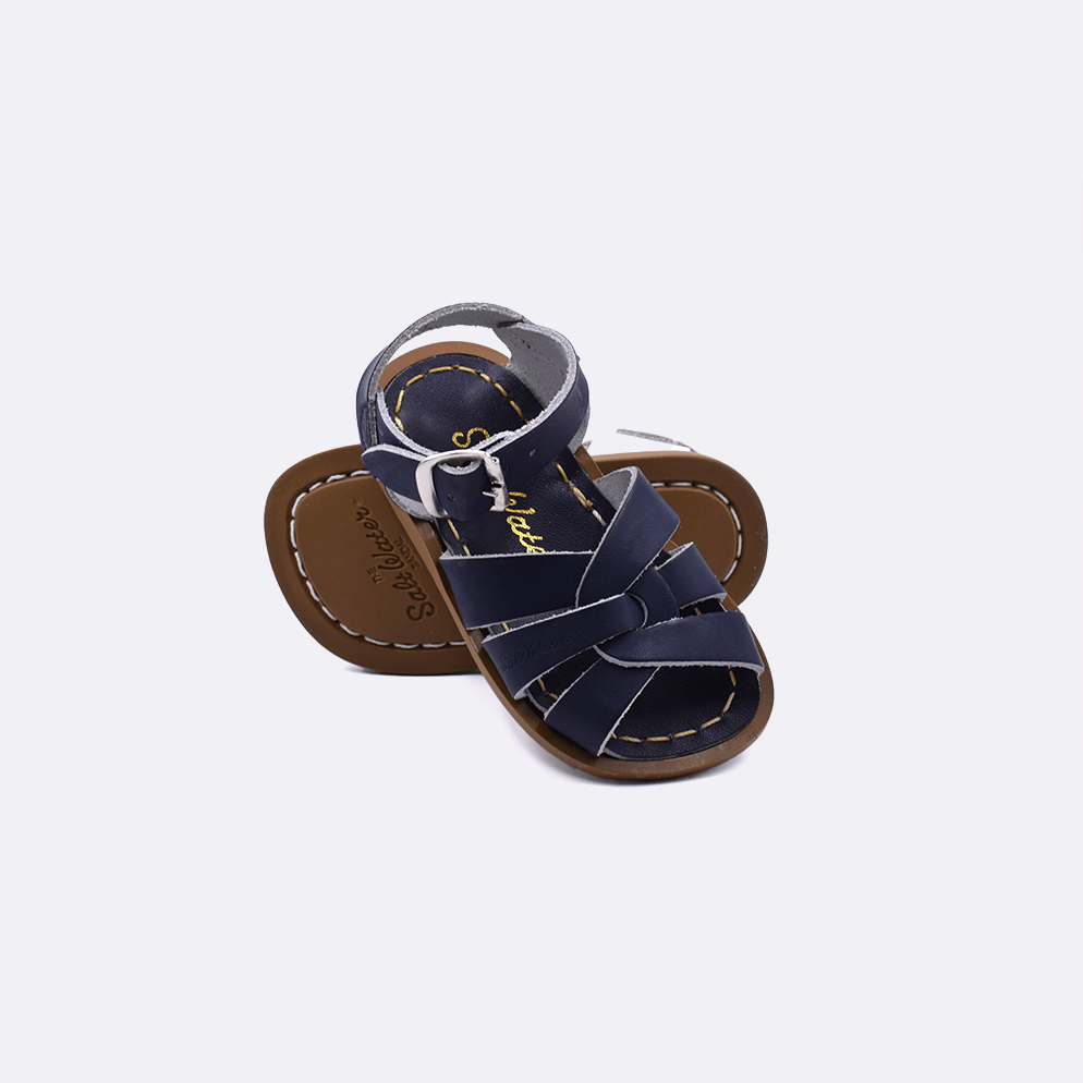 Two baby size 800 Original style sandals color navy.  One standing with the sole facing the camera. The second is laying diagonally over the top left edge of the sole.