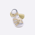 Two toddler sized 8000 Swimmer style sandals with gold straps and white insoles.  One standing with the sole facing the camera. The second is laying diagonally over the top left edge of the sole.