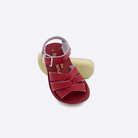 Two toddler sized 8000 Swimmer style sandals with red straps and red insoles.  One standing with the sole facing the camera. The second is laying diagonally over the top left edge of the sole.