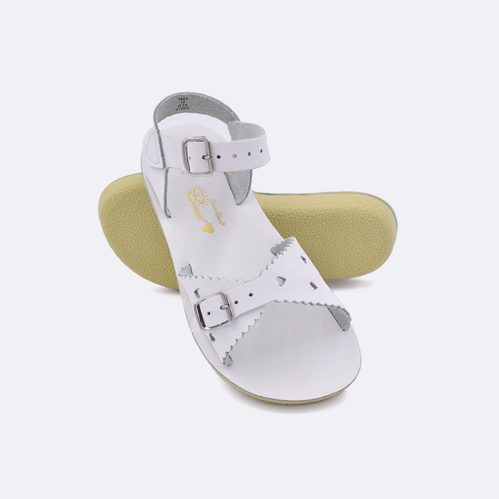 Two little kid sized 1400 Sweetheart style sandals with white straps and white insoles.  One standing with the sole facing the camera. The second is laying diagonally over the top left edge of the sole.