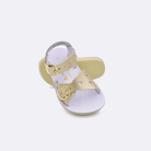 Two toddler sized 1400 Sweetheart style sandals with gold straps and white insoles.  One standing with the sole facing the camera. The second is laying diagonally over the top left edge of the sole.