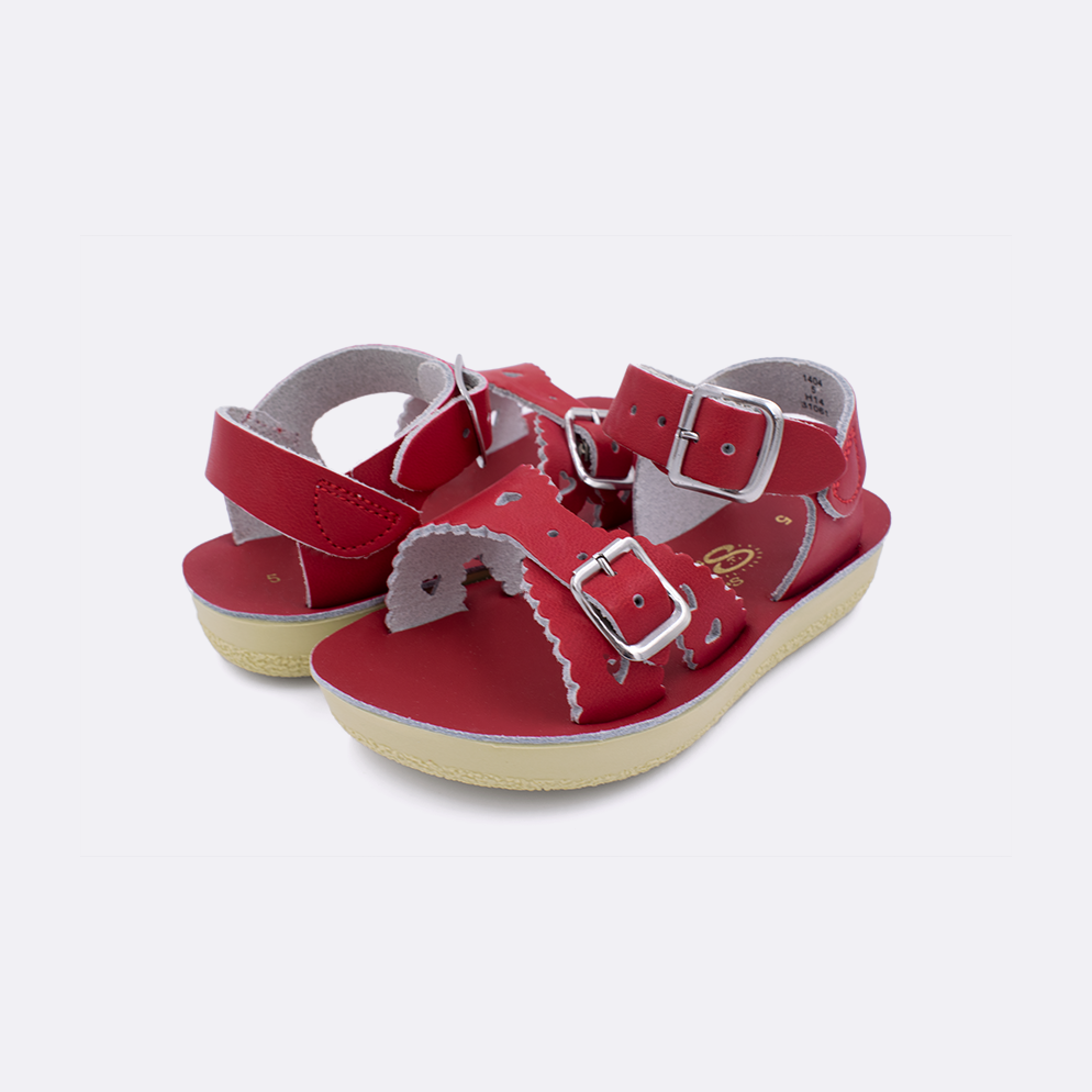 Two toddler sized 1400 Sweetheart style sandals with red straps and red insoles. Both pushed together facing the camera diagonally.
