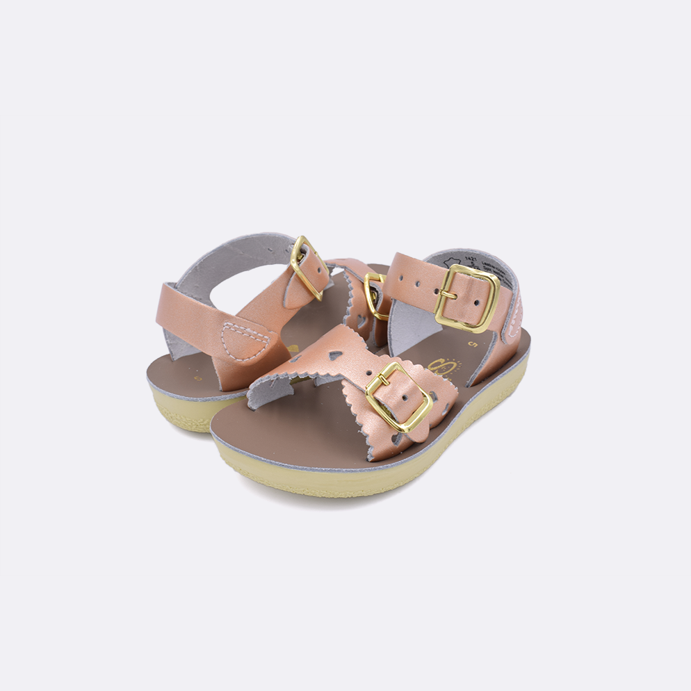 Two toddler sized 1400 Sweetheart style sandals with rose gold straps and beige insoles. Both pushed together facing the camera diagonally.
