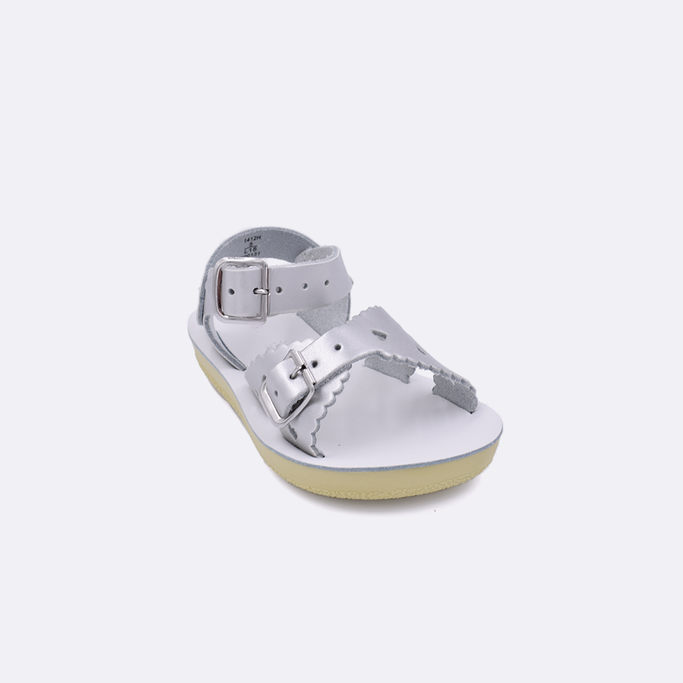 One toddler sized 1400 Sweetheart style sandal with silver straps and a white insole. Facing left to right diagonally. 