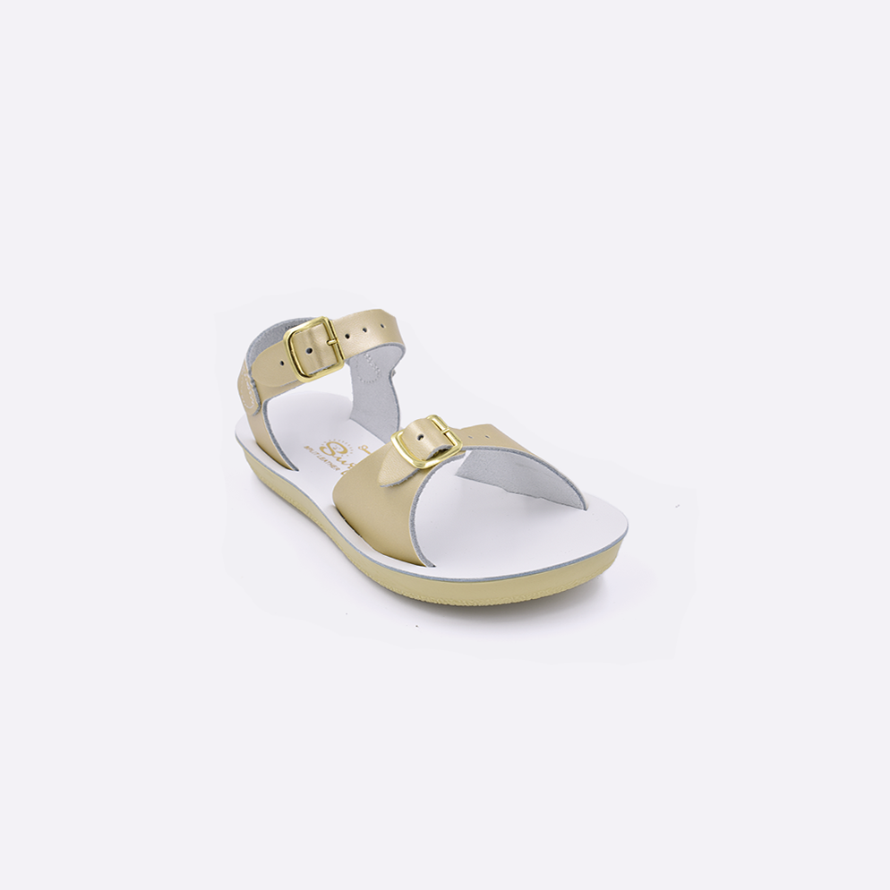 One toddler sized 1700 Surfer style sandal with gold straps and a white insole. Facing left to right diagonally. 