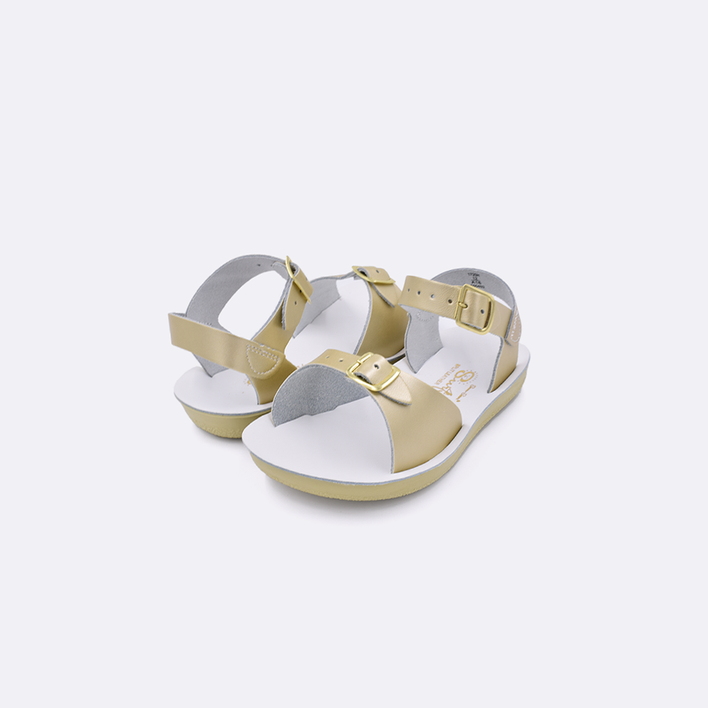 Two toddler sized 1700 Surfer style sandals with gold straps and white insoles. Both pushed together facing the camera diagonally.