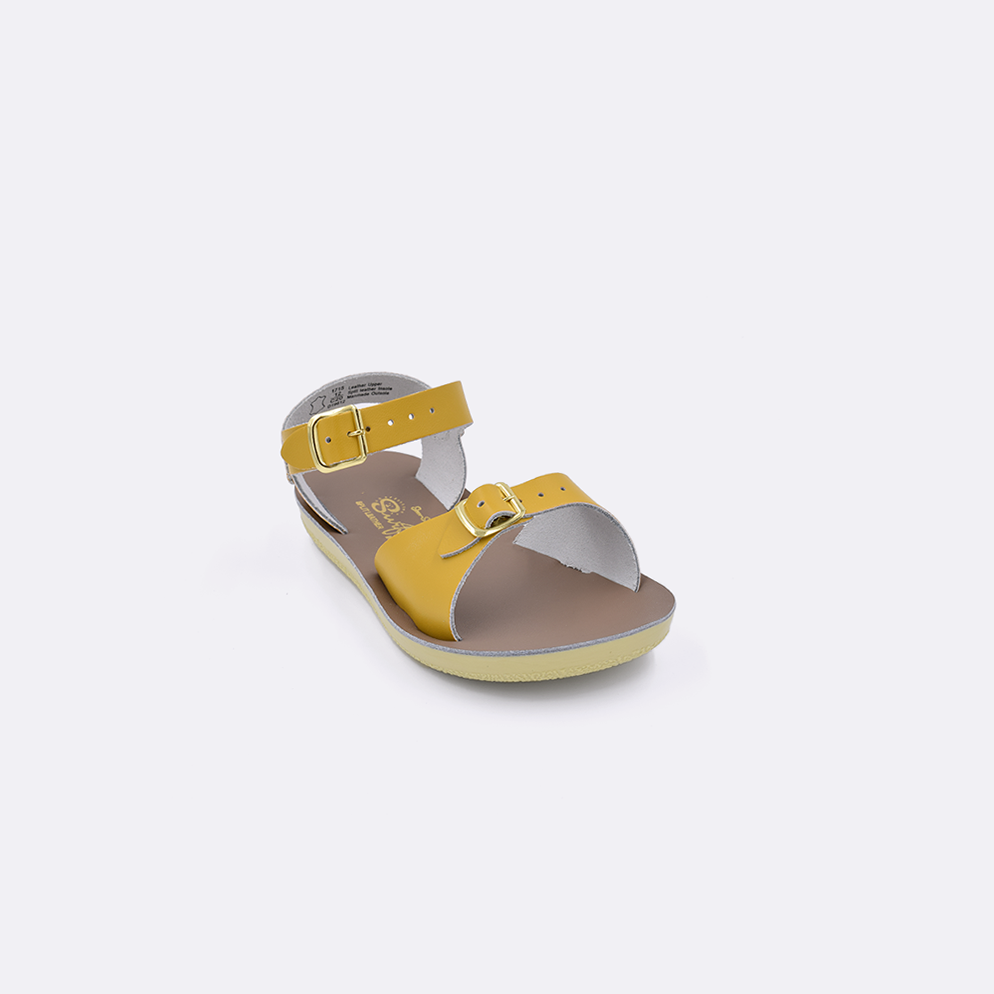 One toddler sized 1700 Surfer style sandal with mustard straps and a beige insole. Facing left to right diagonally. 