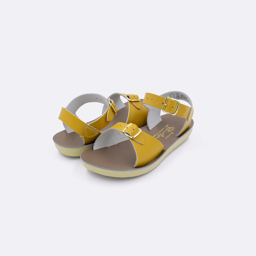 Two  toddler sized 1700 Surfer style sandals with mustard straps and beige insoles. Both pushed together facing the camera diagonally.