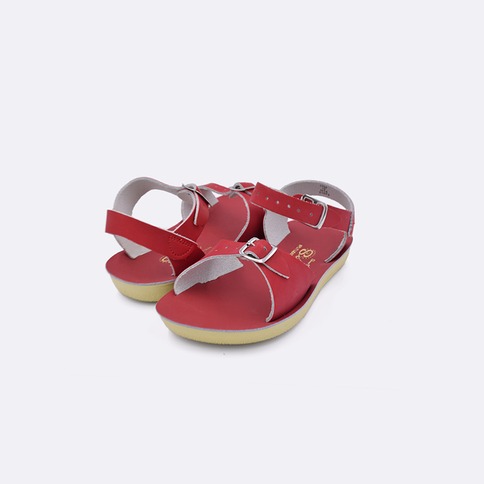 Two toddler sized 1700 Surfer style sandals with red straps and red insoles. Both pushed together facing the camera diagonally.