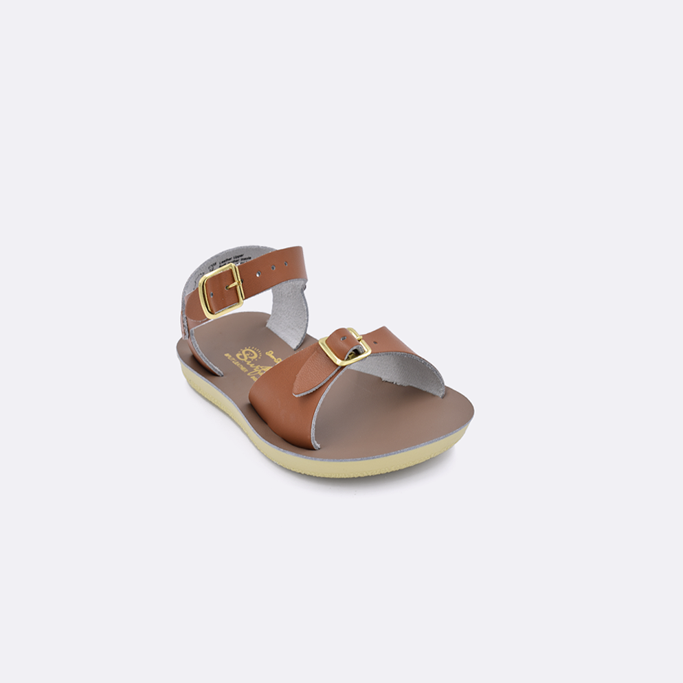 One toddler sized 1700 Surfer style sandal with tan straps and a beige insole. Facing left to right diagonally. 