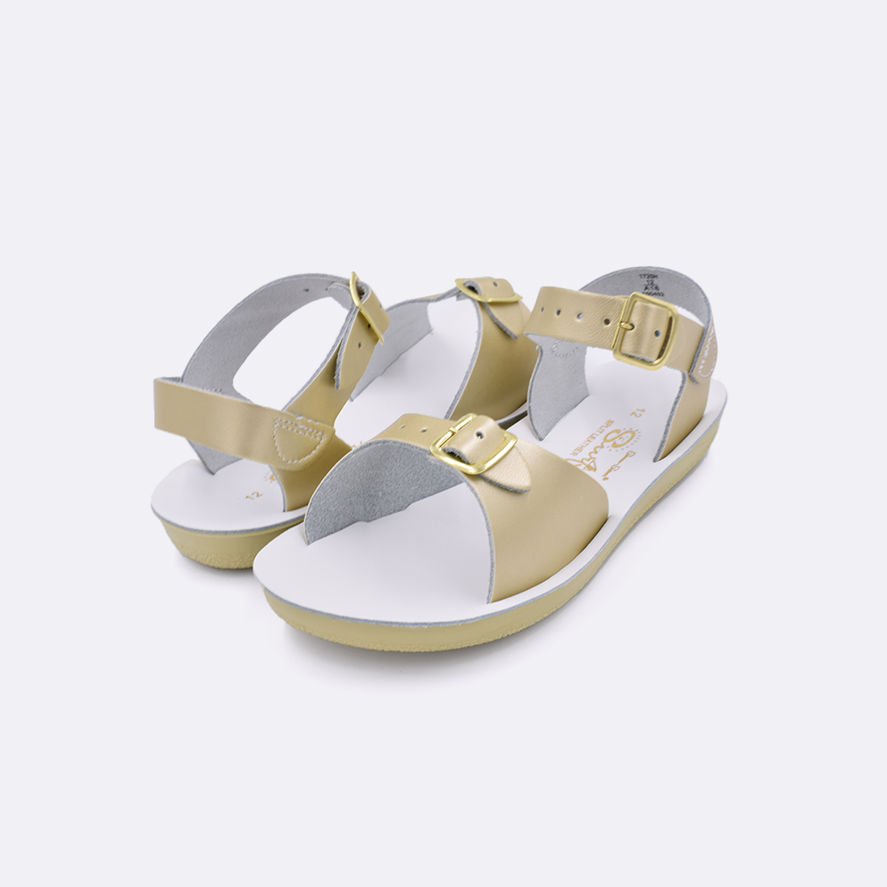 Two little kid sized 1700 Surfer style sandals with gold straps and white insoles. Both pushed together facing the camera diagonally.