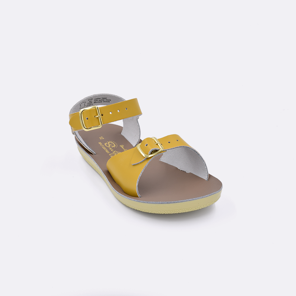 One little kid sized 1700 Surfer style sandal with mustard straps and a beige insole. Facing left to right diagonally. 