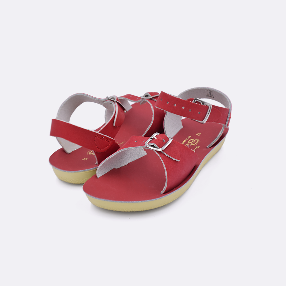 Two little kid sized 1700 Surfer style sandals with red straps and red insoles. Both pushed together facing the camera diagonally.