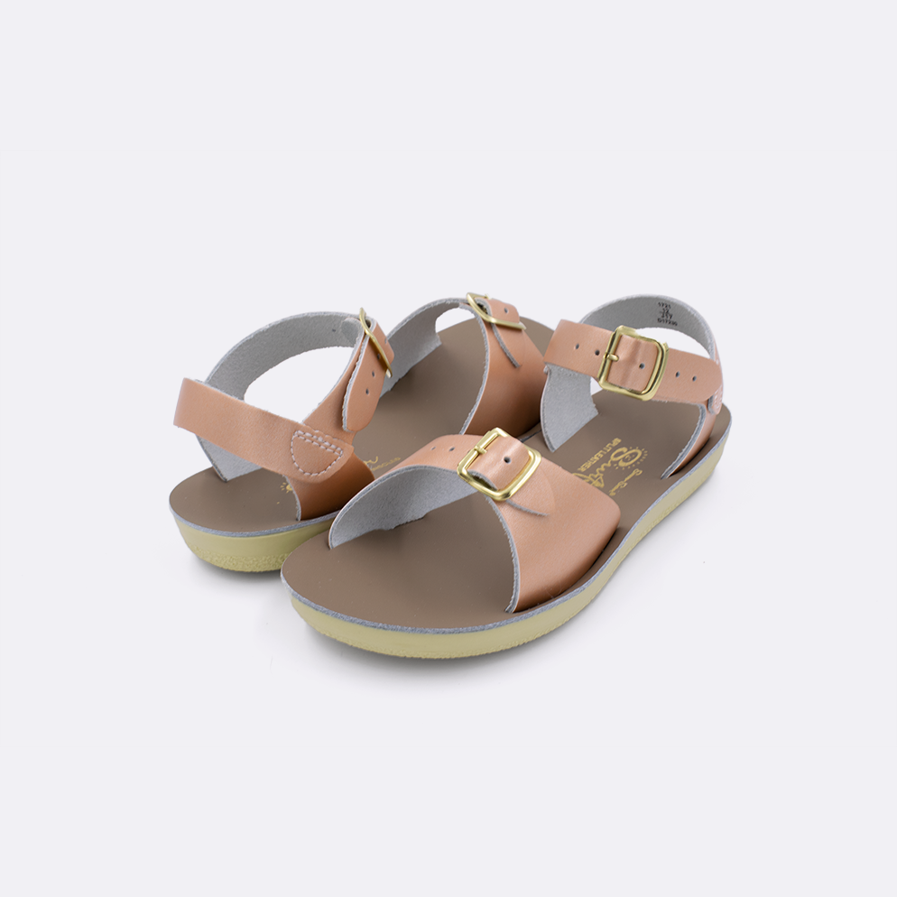 Two little kid sized 1700 Surfer style sandals with rose gold straps and beige insoles. Both pushed together facing the camera diagonally.