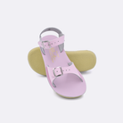 Two little kid sized 1700 Surfer style sandals with shiny pink straps and shiny pink insoles.  One standing with the sole facing the camera. The second is laying diagonally over the top left edge of the sole.