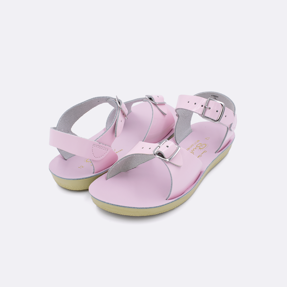 Two little kid sized 1700 Surfer style sandals with shiny pink straps and shiny pink insoles. Both pushed together facing the camera diagonally.