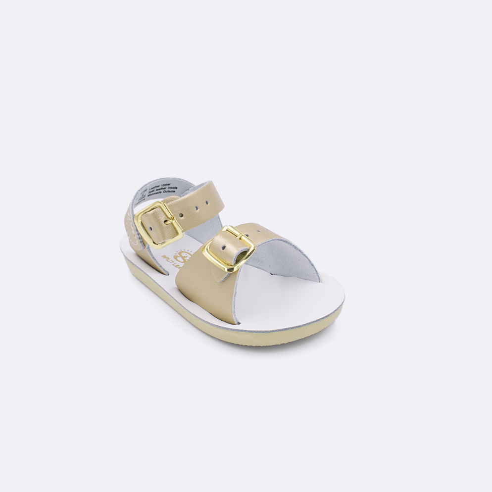 One baby sized 1700 Surfer style sandal with gold straps and a white insole. Facing left to right diagonally. 