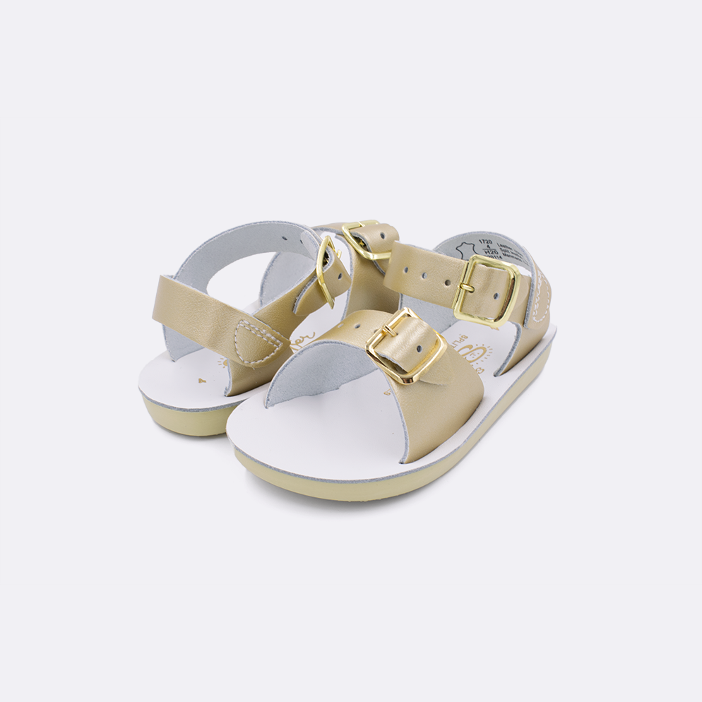 Two baby sized 1700 Surfer style sandals with gold straps and white insoles. Both pushed together facing the camera diagonally.