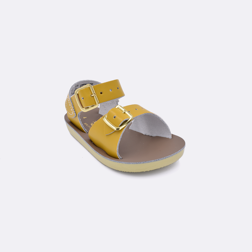 One baby sized 1700 Surfer style sandal with mustard straps and a beige insole. Facing left to right diagonally. 