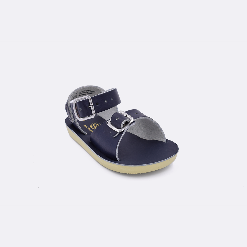 One baby sized 1700 Surfer style sandal with navy straps and a navy insole. Facing left to right diagonally. 
