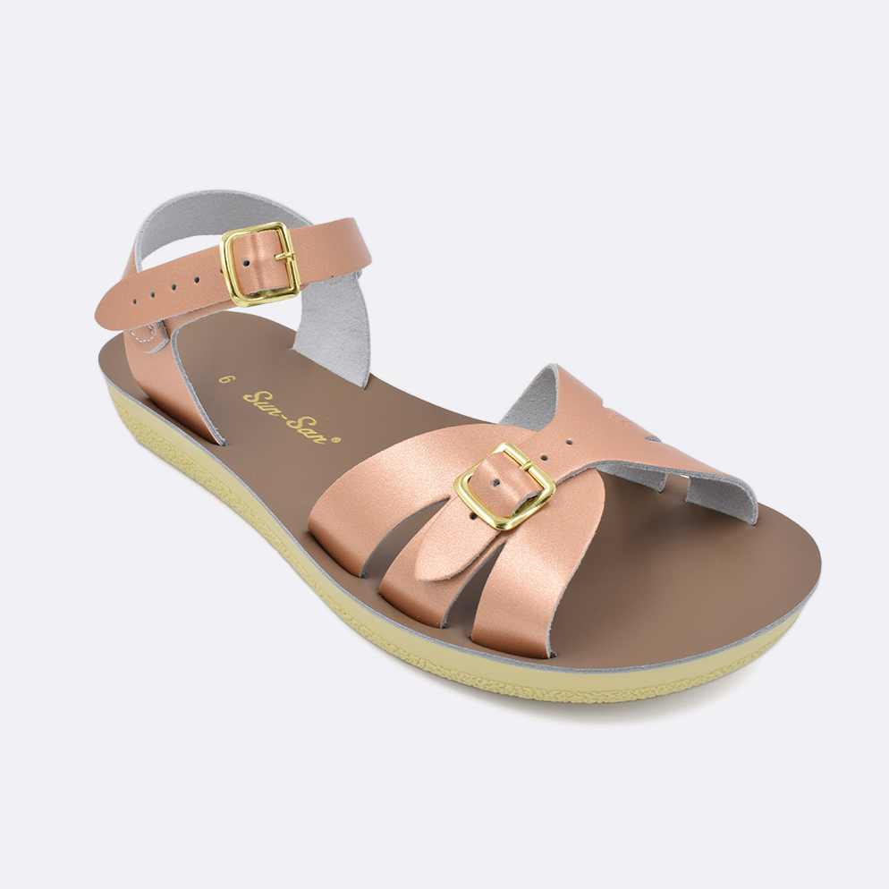 One Women's sized 1900 Boardwalk style sandal with rose gold straps and a beige insole. Facing left to right diagonally. 