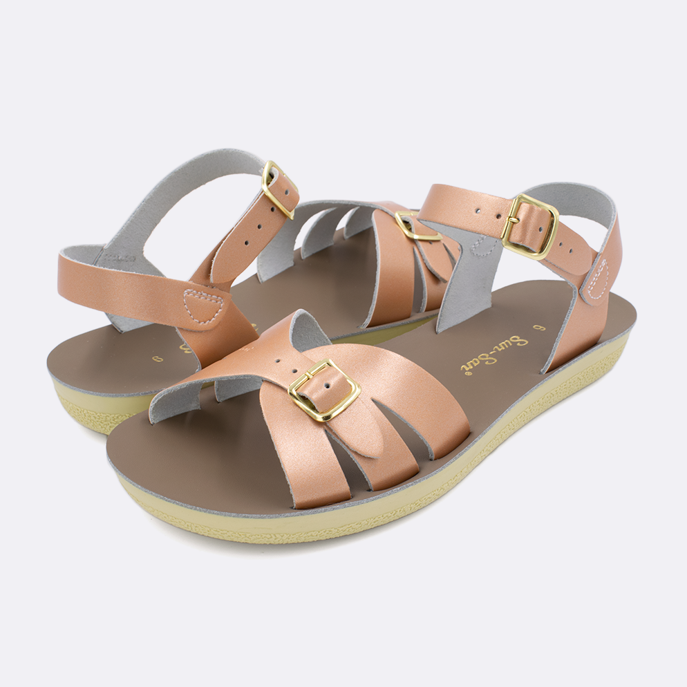 Two Women's sized 1900 Boardwalk style sandals with rose gold straps and beige insoles. Both pushed together facing the camera diagonally.