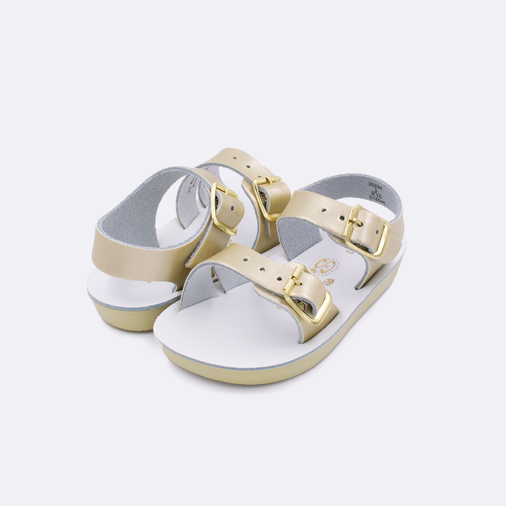 Two baby sized 2000 Sea Wee style sandals with gold straps and white insoles. Both pushed together facing the camera diagonally.