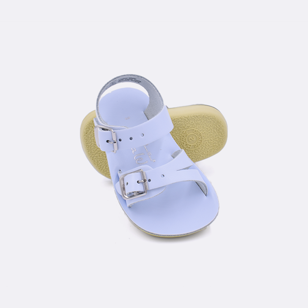 Two baby sized 2000 Sea Wee style sandals with light blue straps and light blue insoles.  One standing with the sole facing the camera. The second is laying diagonally over the top left edge of the sole.