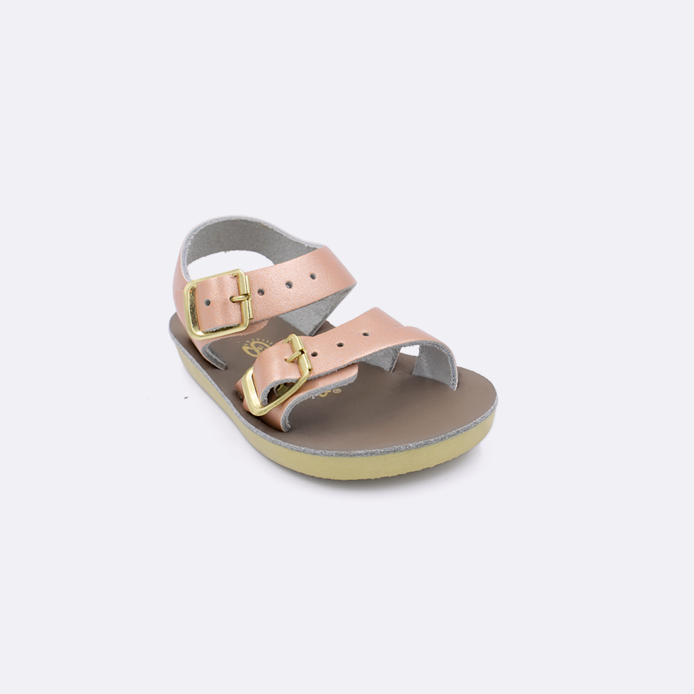 One baby sized 2000 Sea Wee style sandal with rose gold straps and a beige insole. Facing left to right diagonally. 