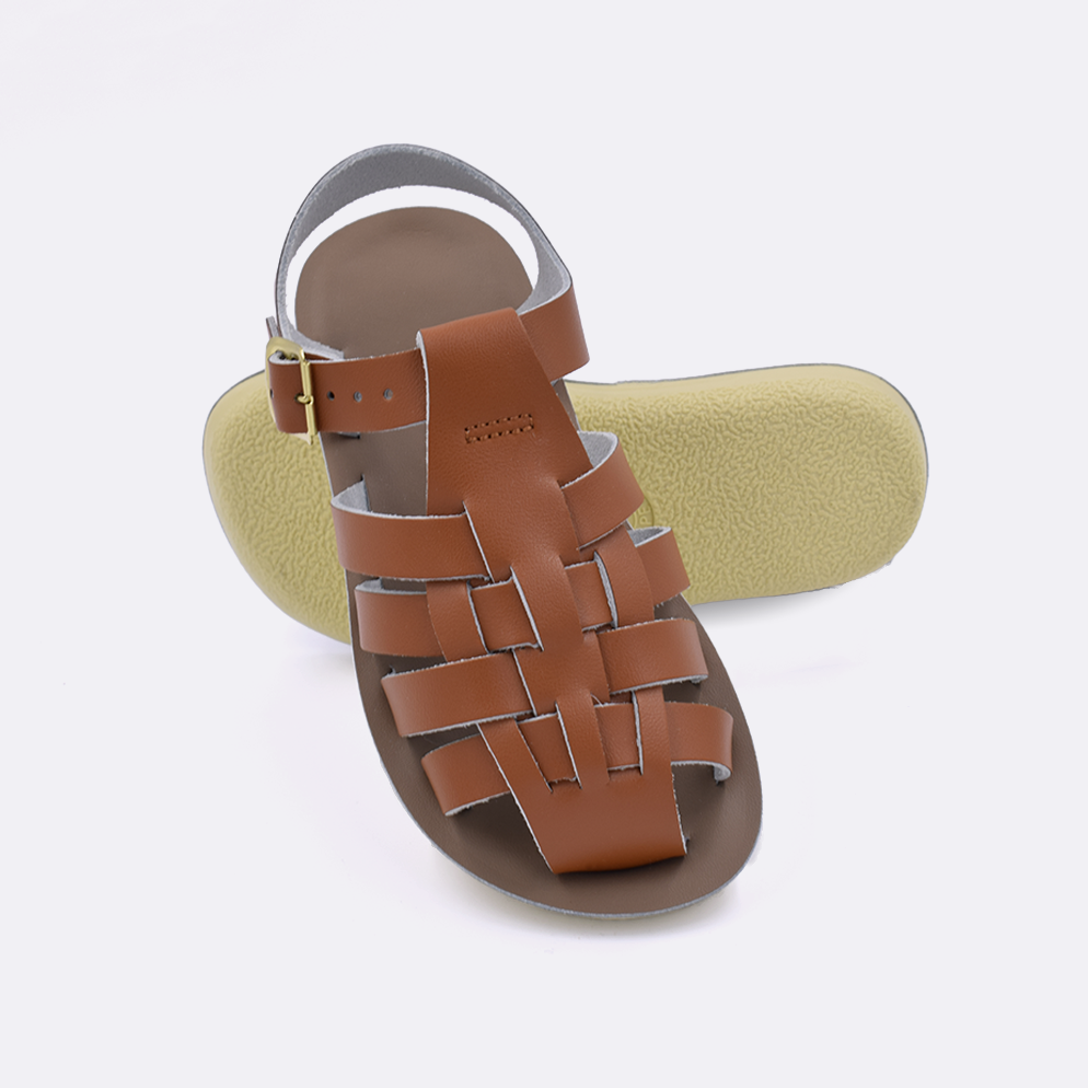 Two little kid sized 4200 Sailor style sandals with tan straps and beige insoles.  One standing with the sole facing the camera. The second is laying diagonally over the top left edge of the sole.