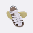 Two little kid sized 4200 Sailor style sandals with white straps and beige insoles.  One standing with the sole facing the camera. The second is laying diagonally over the top left edge of the sole.