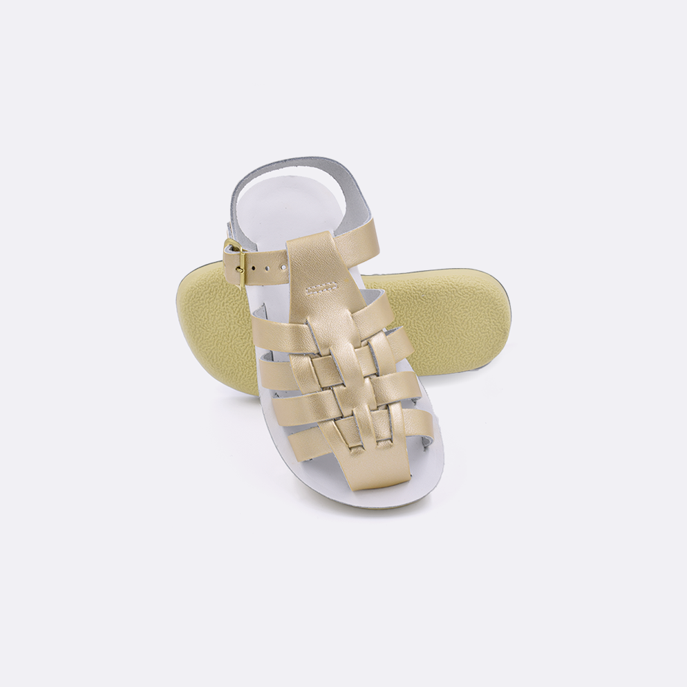 Two toddler sized 4200 Sailor style sandals with gold straps and white insoles.  One standing with the sole facing the camera. The second is laying diagonally over the top left edge of the sole.
