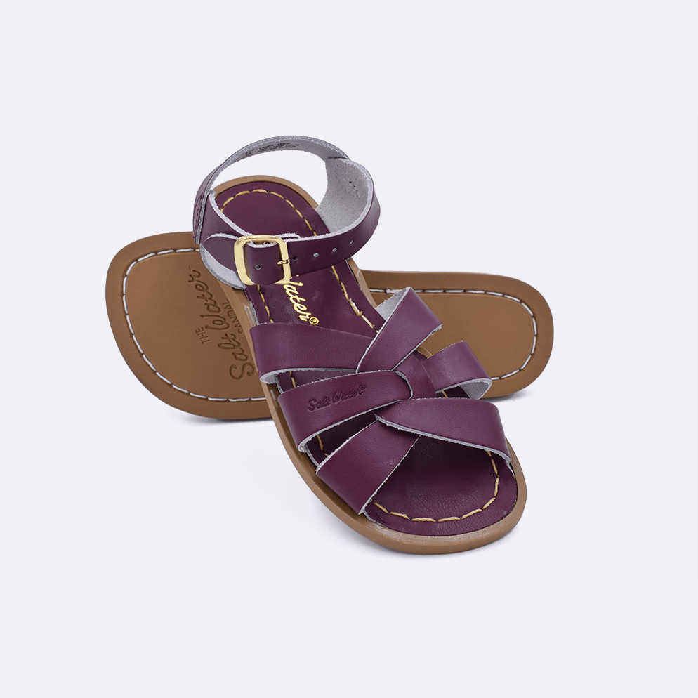 Two claret little kid sized 800 Original style sandals.  One standing with the sole facing the camera. The second is laying diagonally over the top left edge of the sole.