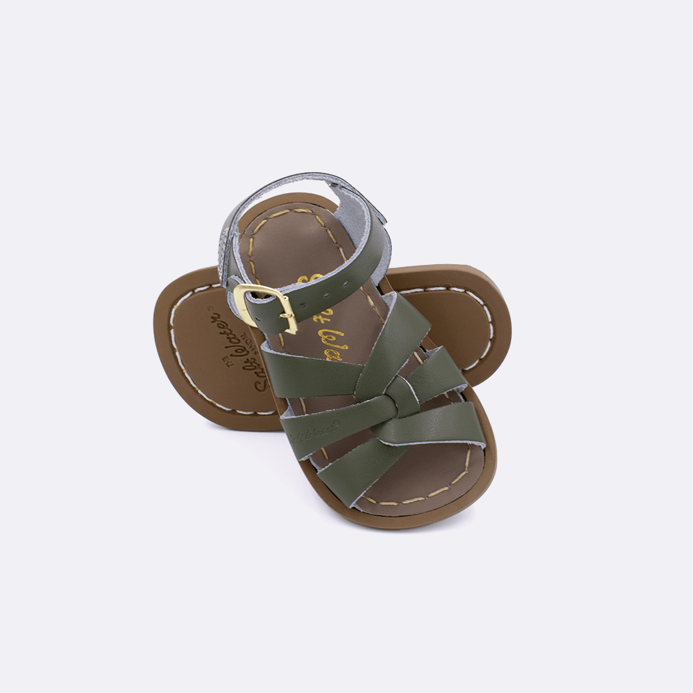 Two baby size 800 Original style sandals color olive.  One standing with the sole facing the camera. The second is laying diagonally over the top left edge of the sole.