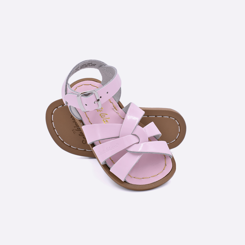 Two toddler sized 800 Original style sandals with shiny pink straps and shiny pink insoles.  One standing with the sole facing the camera. The second is laying diagonally over the top left edge of the sole.