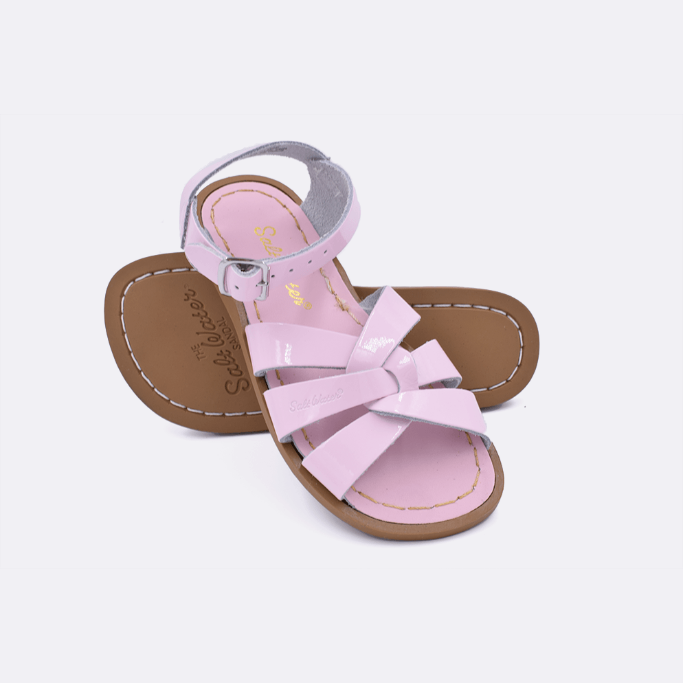 Two shiny pink little kid sized 800 Original style sandals.  One standing with the sole facing the camera. The second is laying diagonally over the top left edge of the sole.
