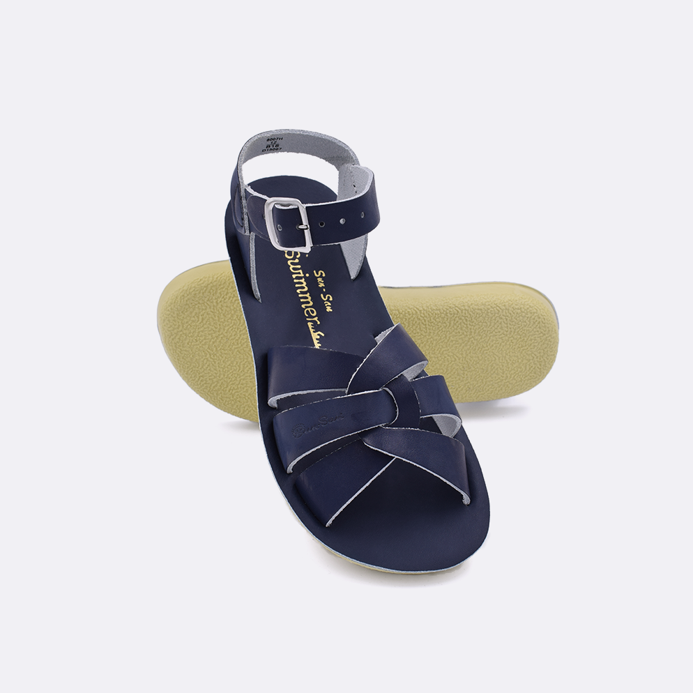 Two little kid sized 8000 Swimmer style sandals with navy straps and navy insoles.  One standing with the sole facing the camera. The second is laying diagonally over the top left edge of the sole.
