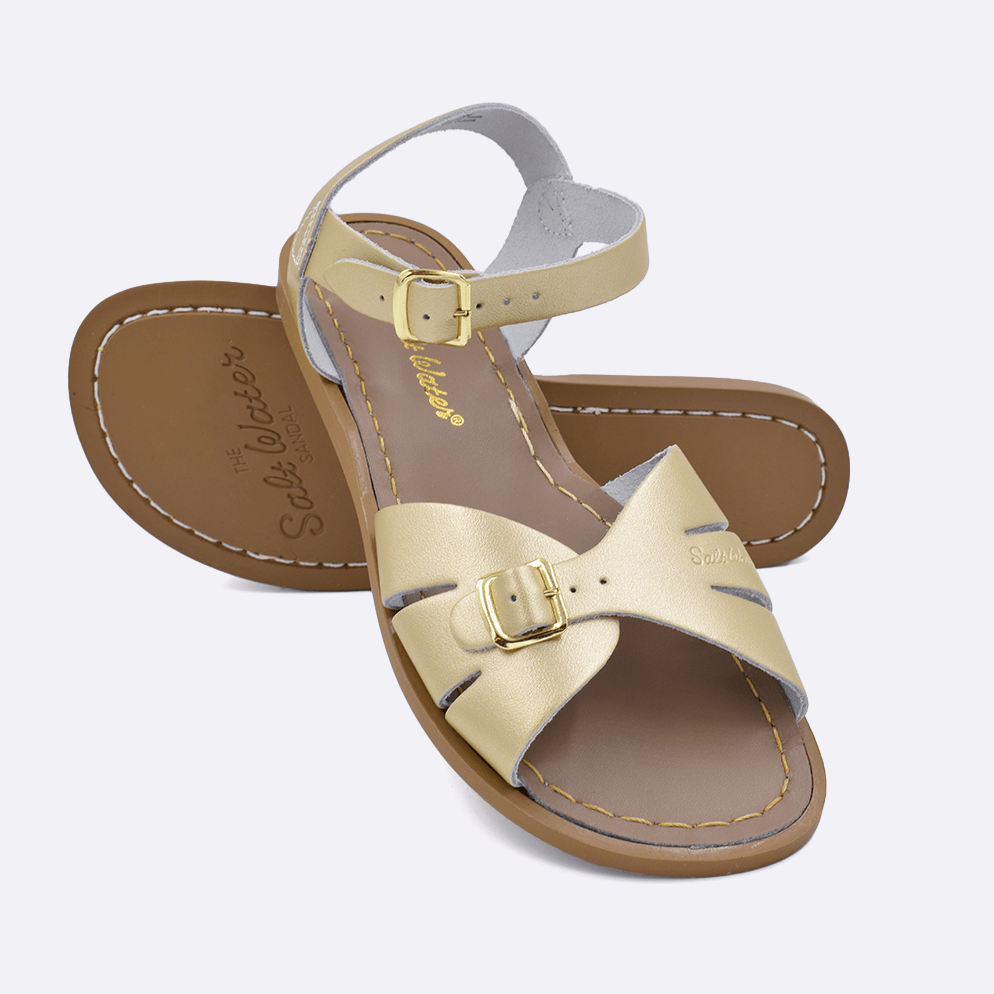 Two 900 Classic style sandals color gold.  One standing with the sole facing the camera. The second is laying diagonally over the top left edge of the sole.	Adult Size.	