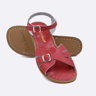 Two 900 Classic style sandals color red.  One standing with the sole facing the camera. The second is laying diagonally over the top left edge of the sole.	Adult Size.