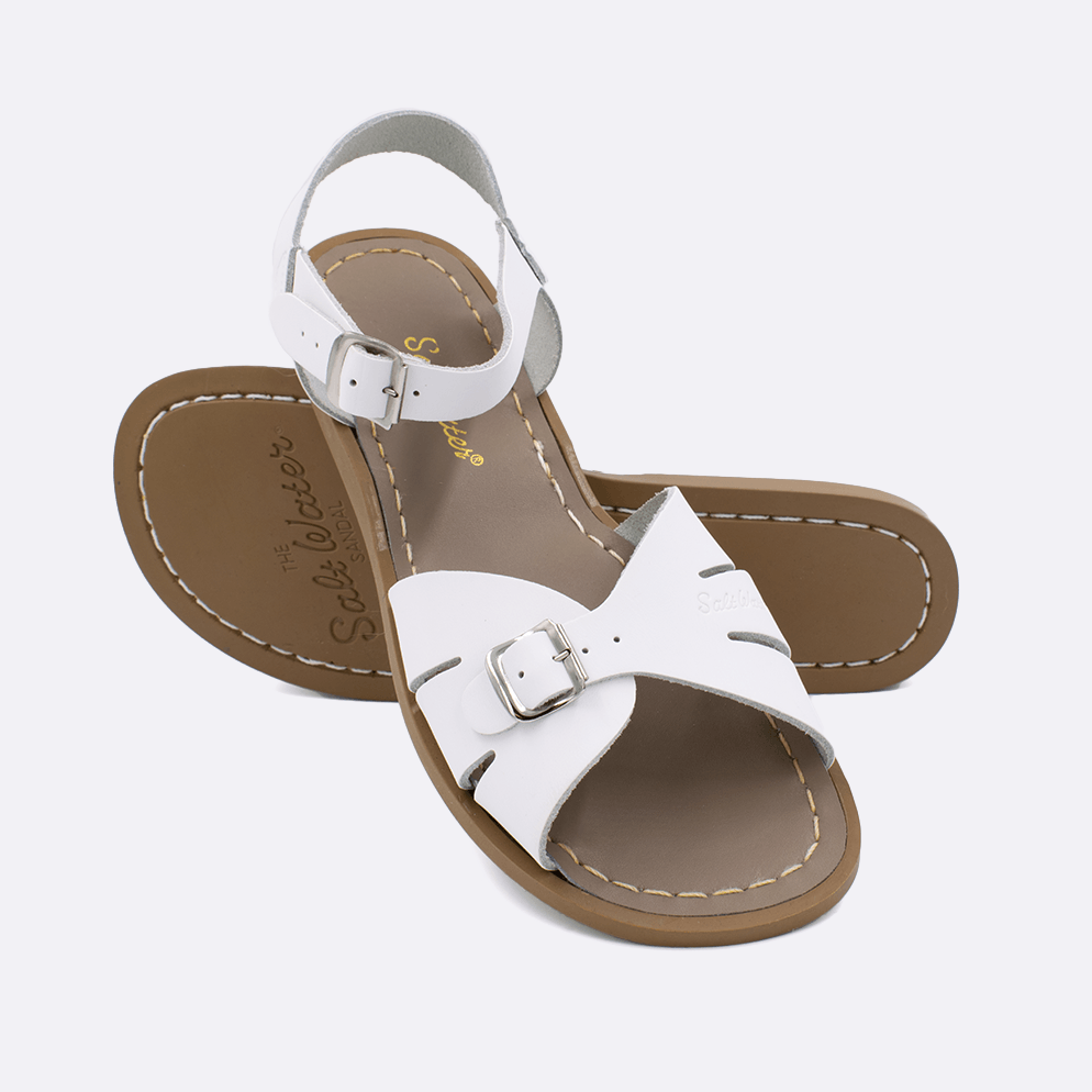 Two 900 Classic style sandals color white.  One standing with the sole facing the camera. The second is laying diagonally over the top left edge of the sole.	Adult Size.	