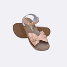 Two 900 Classic style sandals color rose gold.  One standing with the sole facing the camera. The second is laying diagonally over the top left edge of the sole.	Little Kid Size.