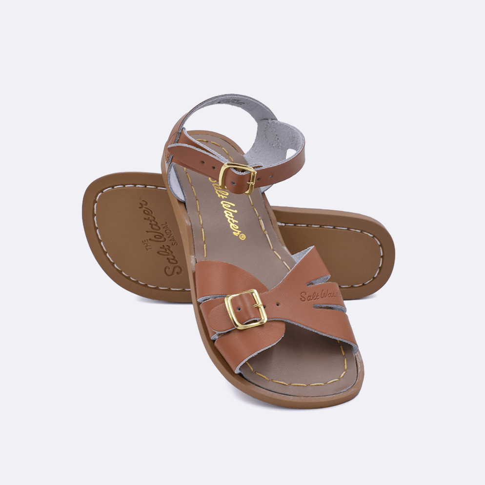 Two 900 Classic style sandals color tan.  One standing with the sole facing the camera. The second is laying diagonally over the top left edge of the sole.	Little Kid Size.