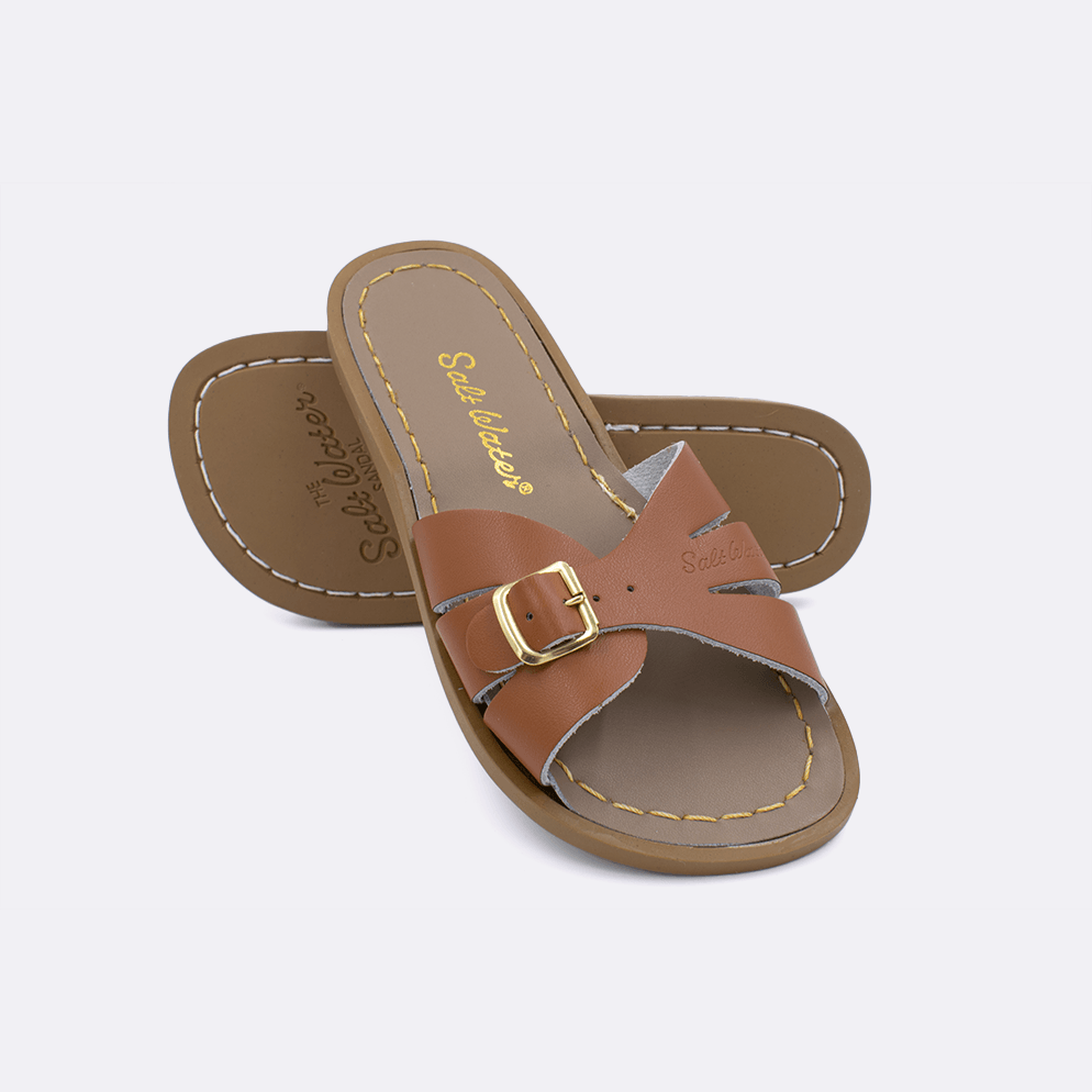 Two 9900 Classic Slide style sandals color tan.  One standing with the sole facing the camera. The second is laying diagonally over the top left edge of the sole.	Little Kid Size.