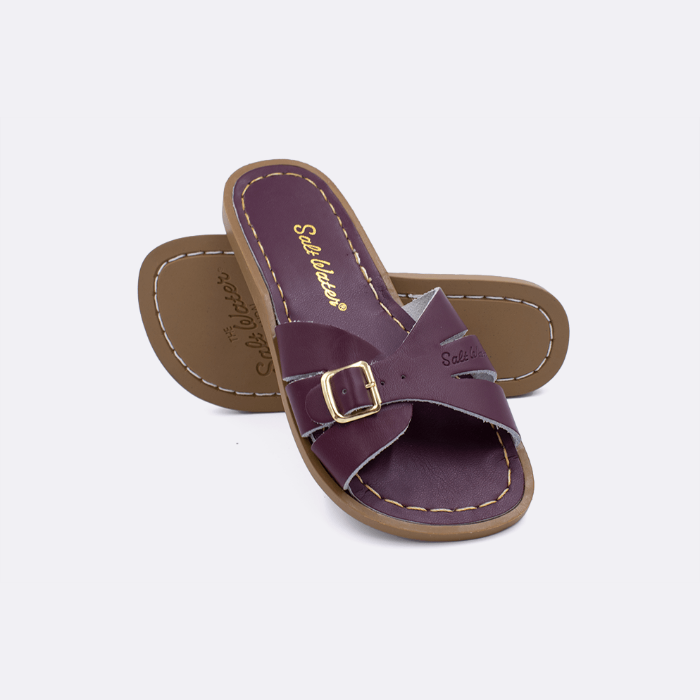 Two 9900 Classic Slide style sandals color claret.  One standing with the sole facing the camera. The second is laying diagonally over the top left edge of the sole.	Little Kid Size.