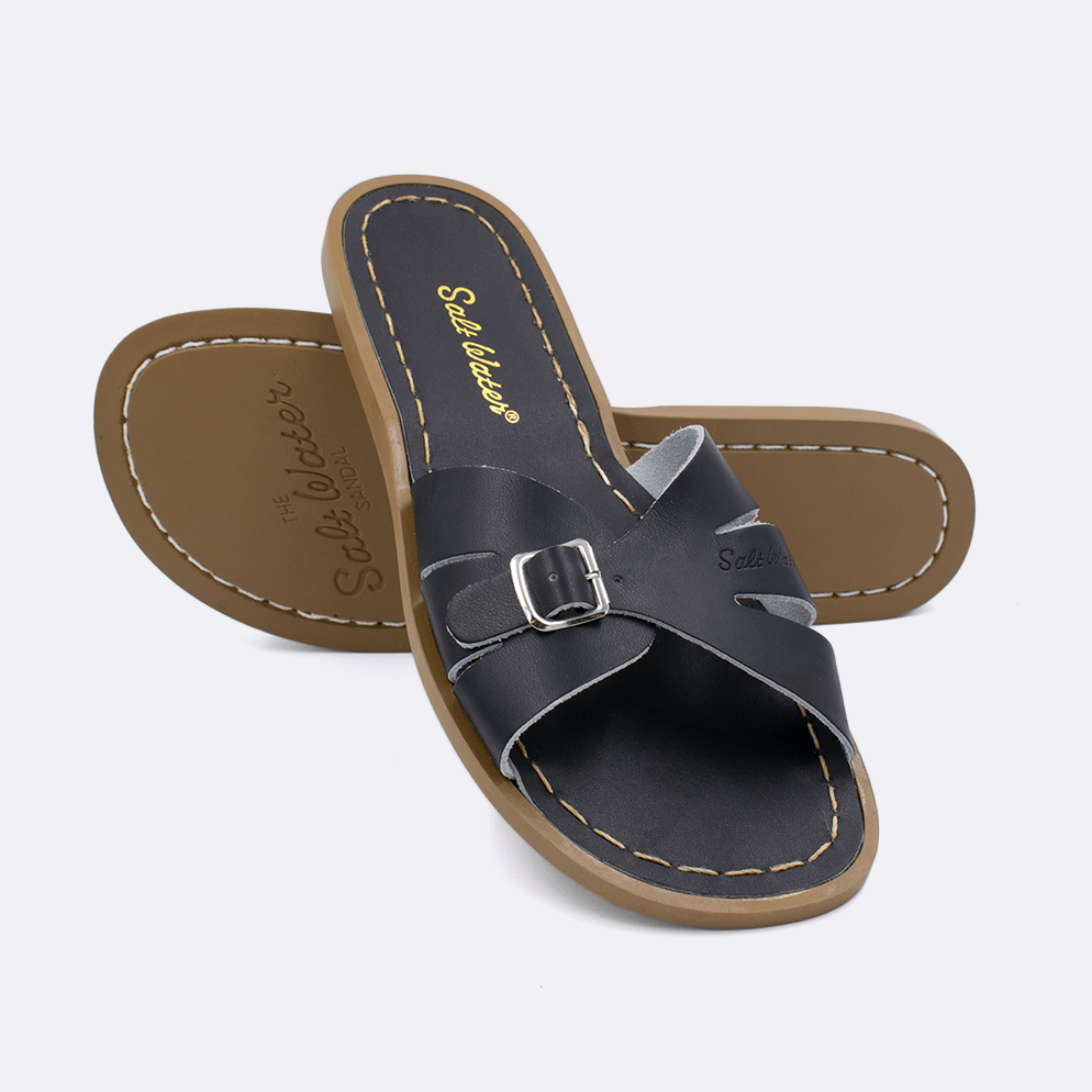 Two 9900 Classic Slide style sandals color black.  One standing with the sole facing the camera. The second is laying diagonally over the top left edge of the sole.	Adult Size.